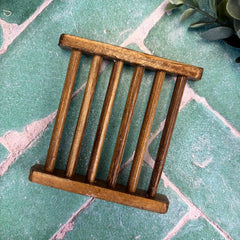 Small wooden soap tray on a textured green surface with decorative elements. Calhoun Farmstead DuBois Pa