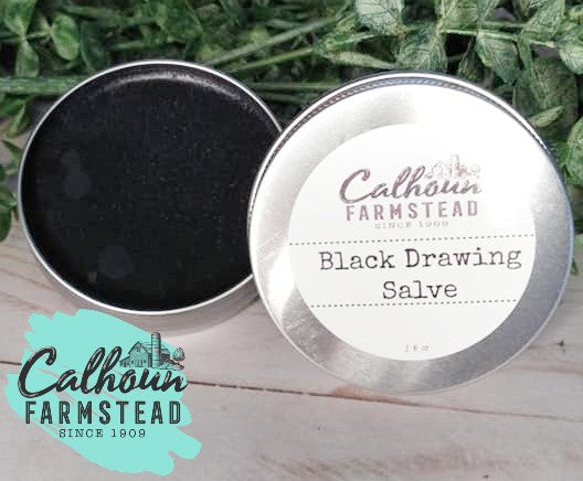 Black drawing salve in tin. Open lid to see salve. Salve is made with herbs, activated charcoal, clays and oils. 